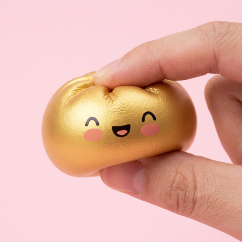 Dumpling Squishy Gold Lucky puristettuna kädessä, squishy-materiaali